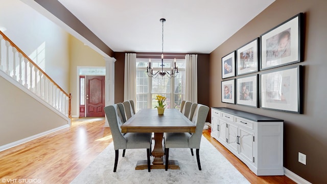 7272 Holden Rd, Stevensville, MI 49127 - dining room with light wood-style floors, baseboards, stairs, and a notable chandelier