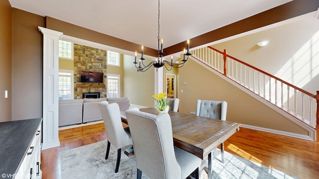 7272 Holden Rd, Stevensville, MI 49127 - dining area featuring an inviting chandelier, wood finished floors, a fireplace, and stairs