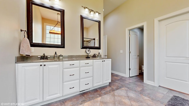 7272 Holden Rd, Stevensville, MI 49127 - full bath with baseboards, stone finish floor, double vanity, and a sink
