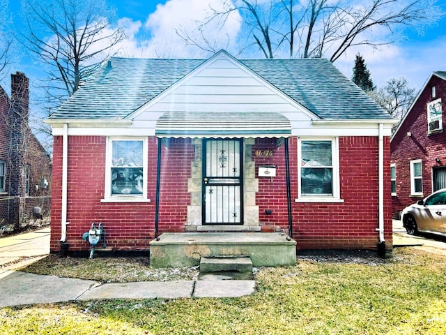 16476 Rossini Dr, Detroit, MI 48205 - bungalow featuring brick siding, roof with shingles, and a front lawn
