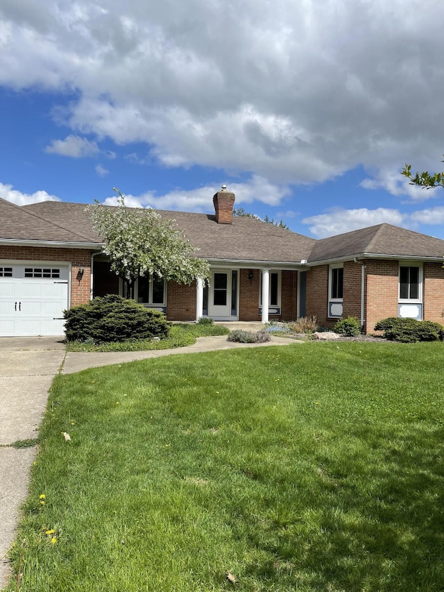 ranch-style home featuring an attached garage, a chimney, concrete driveway, a front lawn, and brick siding