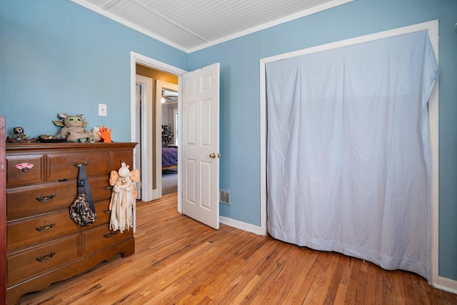 bedroom featuring baseboards, crown molding, light wood-style flooring, and visible vents