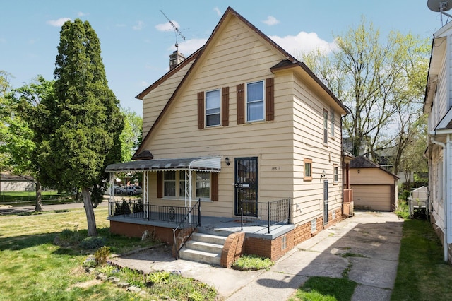 view of front of property with a chimney, an outbuilding, covered porch, a garage, and a front yard