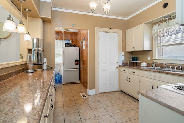 kitchen with freestanding refrigerator, visible vents, a sink, white cabinetry, and crown molding