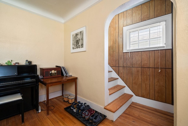 staircase featuring ornamental molding, arched walkways, and wood finished floors