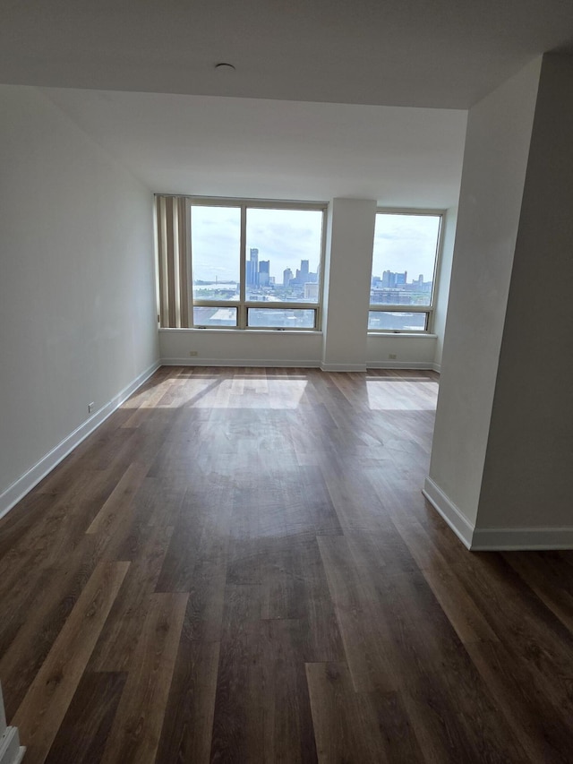 3320 Spinnaker Ln Unit 15E, Detroit, MI 48207 - empty room with dark wood-style flooring, baseboards, and a skyline view