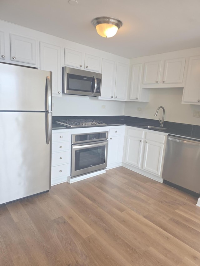 3320 Spinnaker Ln Unit 15E, Detroit, MI 48207 - kitchen featuring stainless steel appliances, a sink, dark countertops, and white cabinets