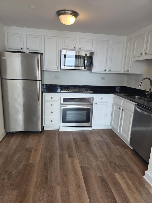 3320 Spinnaker Ln Unit 15E, Detroit, MI 48207 - kitchen with appliances with stainless steel finishes, a sink, dark countertops, and dark wood-type flooring