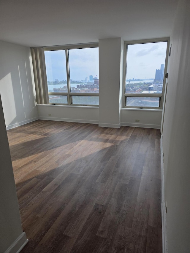 3320 Spinnaker Ln Unit 15E, Detroit, MI 48207 - unfurnished room with healthy amount of natural light, dark wood-style flooring, baseboards, and a city view