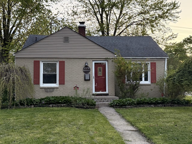 bungalow-style house with a chimney, brick siding, and a front yard