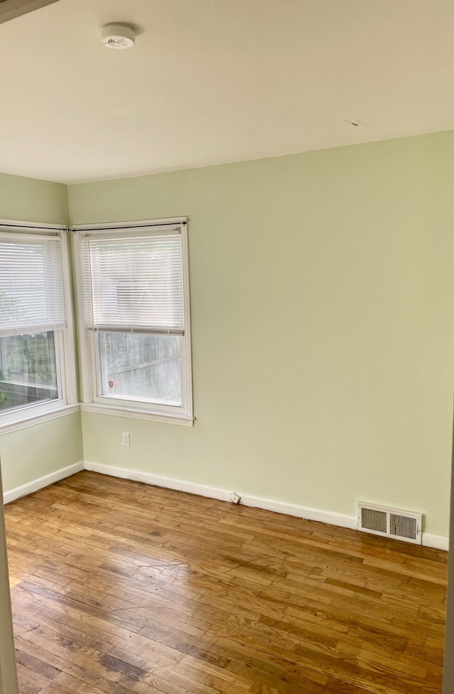empty room featuring baseboards, wood finished floors, and plenty of natural light