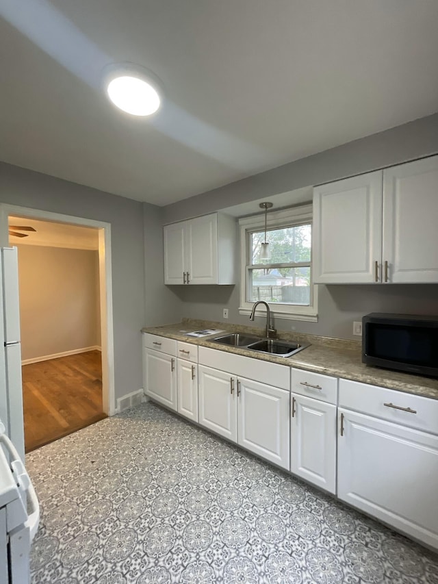 2575 Ellwood Ave, Berkley, MI 48072 - kitchen featuring a sink, white cabinetry, baseboards, freestanding refrigerator, and stove