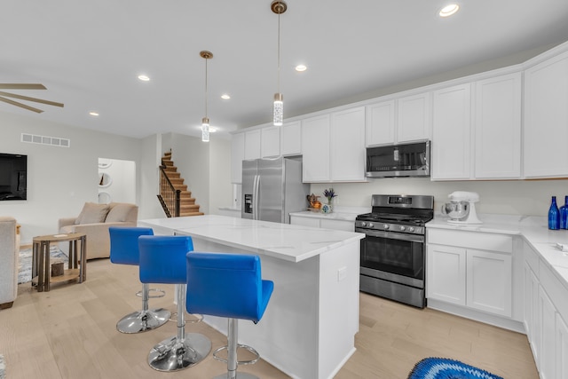 3166 Roma, Wixom, MI 48393 - kitchen with appliances with stainless steel finishes, open floor plan, a kitchen island, white cabinets, and recessed lighting