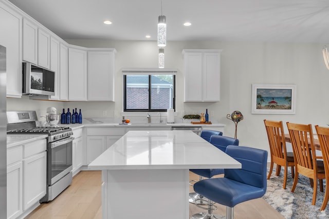 3166 Roma, Wixom, MI 48393 - kitchen featuring appliances with stainless steel finishes, a breakfast bar area, a sink, a kitchen island, and white cabinets