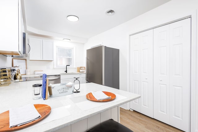 21430 Ridgedale St, Oak Park, MI 48237 - kitchen with a sink, a peninsula, visible vents, white cabinetry, and appliances with stainless steel finishes