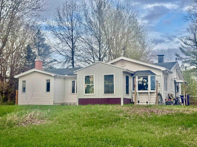 view of home's exterior with a chimney and a yard