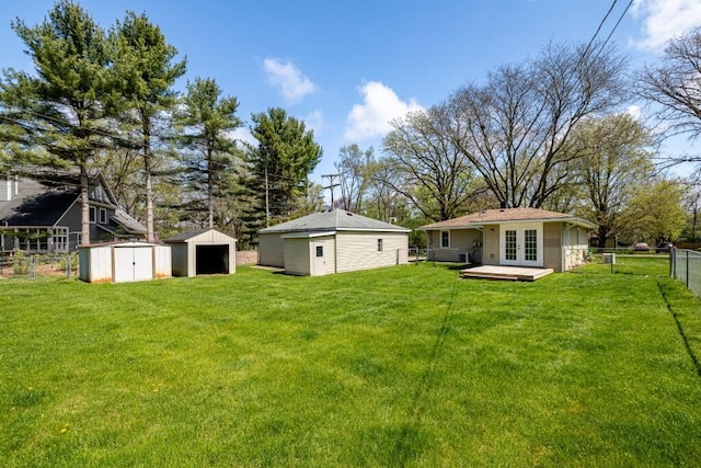 view of yard featuring french doors, an outdoor structure, a garage, fence private yard, and a storage shed