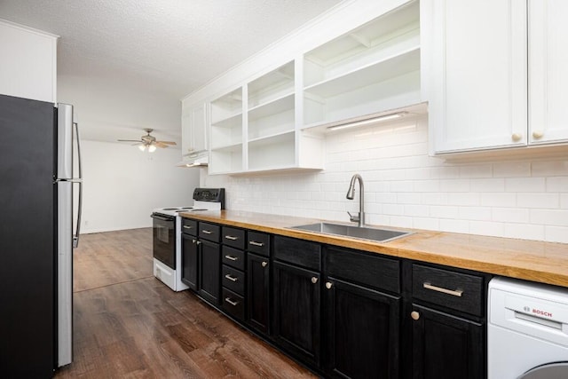 kitchen featuring freestanding refrigerator, washer / clothes dryer, dark cabinets, a sink, and electric range