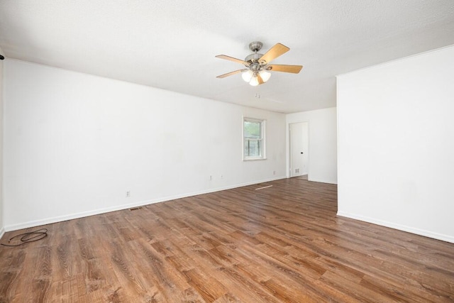 spare room featuring a ceiling fan, baseboards, and wood finished floors