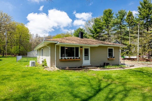 back of house with a lawn, a chimney, and central AC