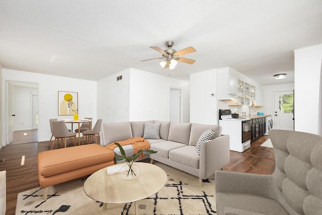 living room with a ceiling fan, visible vents, and wood finished floors