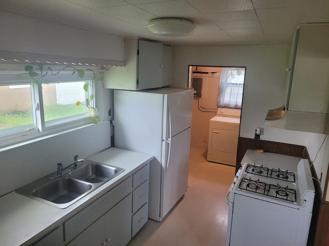 kitchen featuring washer / dryer, white appliances, a sink, and healthy amount of natural light