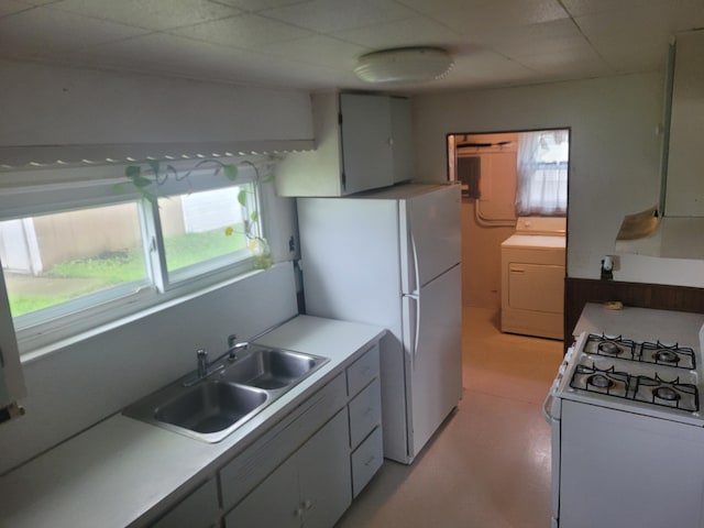 kitchen with white appliances, washer / clothes dryer, a sink, light countertops, and exhaust hood