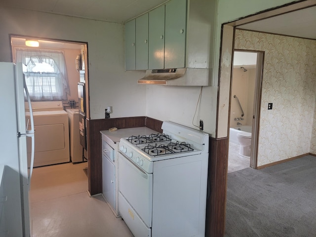 kitchen with white appliances, washing machine and clothes dryer, wallpapered walls, under cabinet range hood, and light carpet