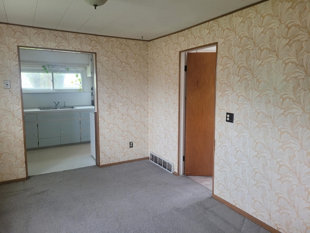 unfurnished room featuring carpet flooring, visible vents, wallpapered walls, and a sink