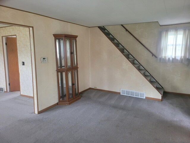unfurnished living room with carpet floors, stairway, and baseboards