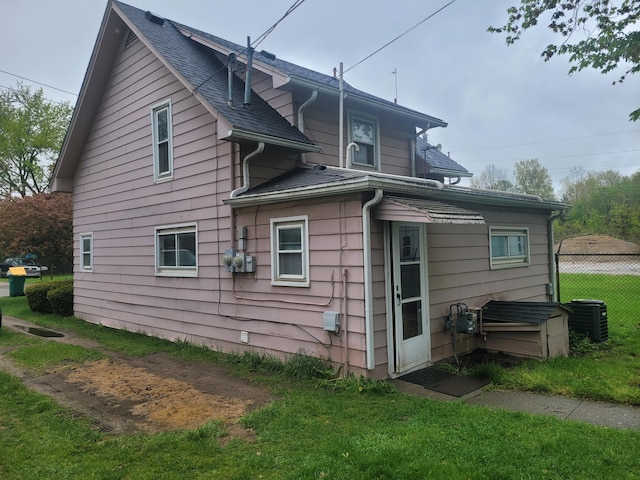 back of property with central air condition unit and a shingled roof