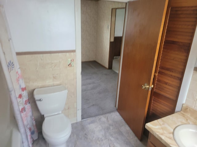 full bathroom featuring wainscoting, vanity, and toilet