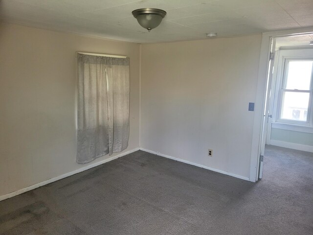 spare room with dark colored carpet and baseboards
