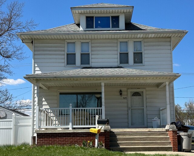 traditional style home with a porch and roof with shingles