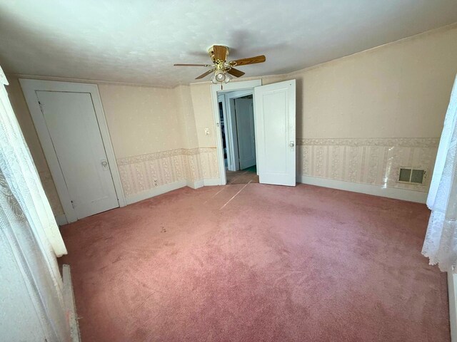 unfurnished bedroom featuring carpet, wallpapered walls, and a ceiling fan