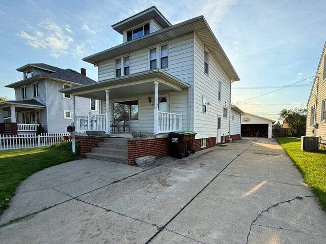 american foursquare style home with covered porch, an outdoor structure, cooling unit, and a garage