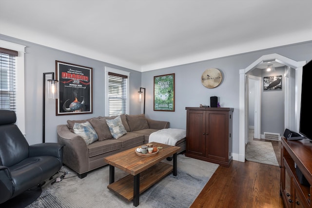 living area featuring wood finished floors, arched walkways, and baseboards