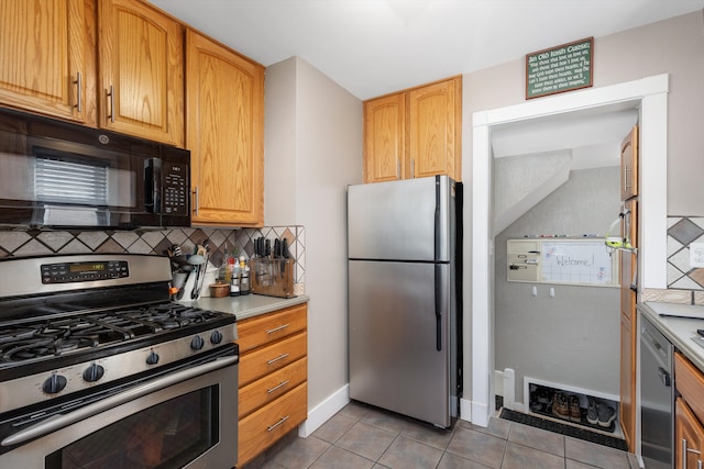 kitchen with light tile patterned floors, stainless steel appliances, baseboards, light countertops, and decorative backsplash