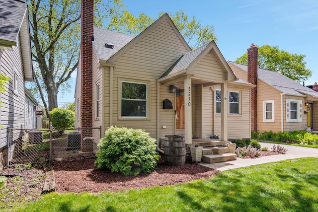 view of front of home with a chimney, cooling unit, and roof with shingles