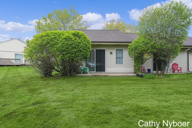rear view of house with a lawn, a patio area, and roof with shingles