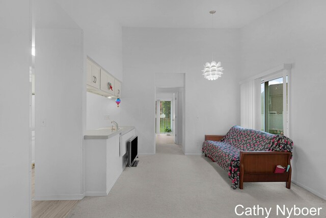 living area with healthy amount of natural light, a high ceiling, baseboards, and light colored carpet