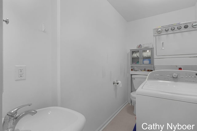 laundry area with stacked washer and clothes dryer and baseboards
