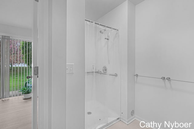 bathroom featuring a shower stall and baseboards