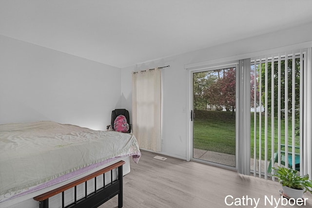 bedroom with access to exterior and wood finished floors