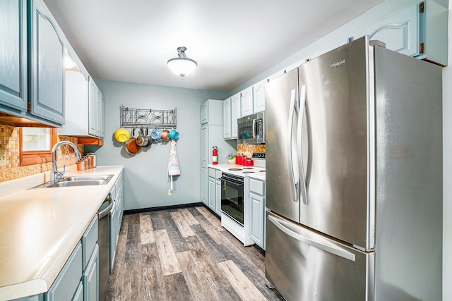 kitchen with backsplash, appliances with stainless steel finishes, dark wood-style flooring, and a sink