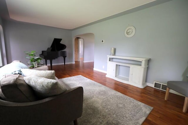living area with arched walkways, wood finished floors, and baseboards