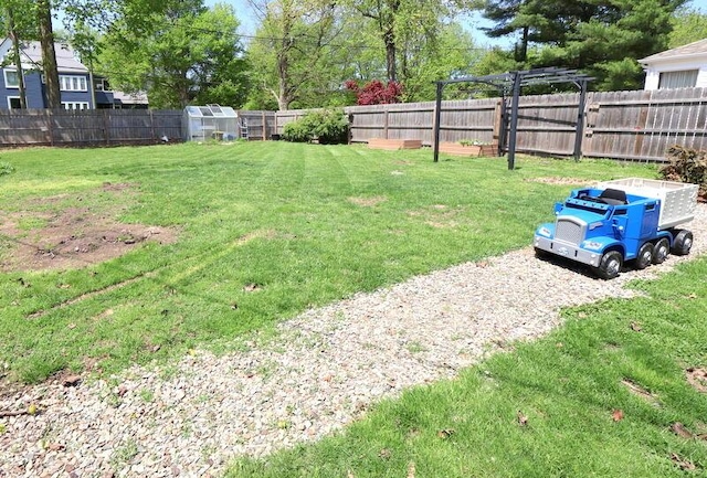 view of yard with a greenhouse and an outbuilding