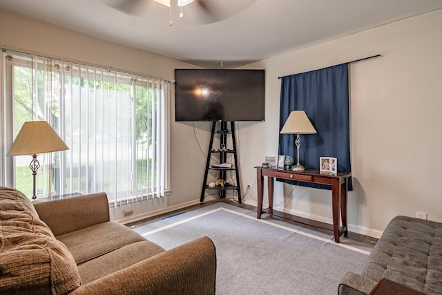 living area featuring a ceiling fan, healthy amount of natural light, and baseboards