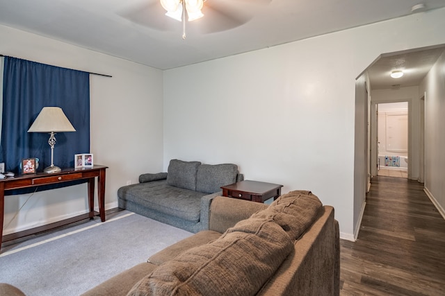 living area featuring arched walkways, a ceiling fan, baseboards, and wood finished floors