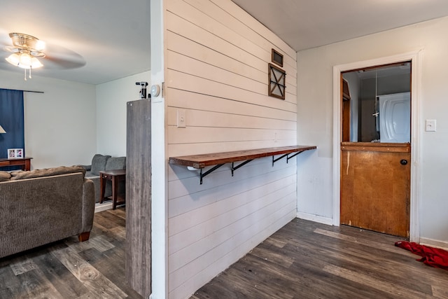 hallway with dark wood finished floors and wood walls